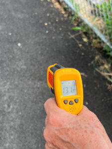 Infrared sensor reads surface temperatures. Asphalt path in the sun shows 131º